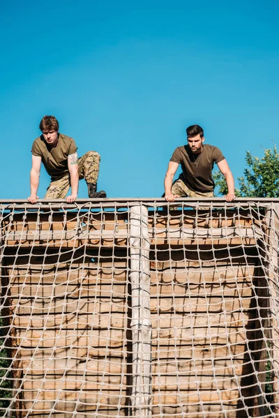 Low angle view of young soldiers practicing during obstacle run on range — Stock Photo