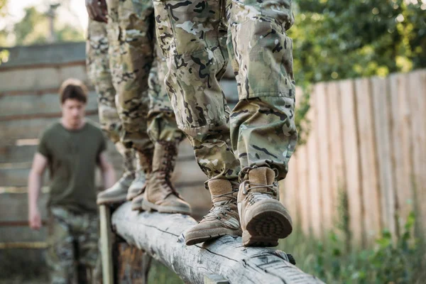 Tiro recortado de soldados en uniforme militar practicando en carrera de obstáculos en el rango - foto de stock