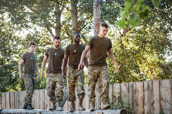 Soldats multiethniques en uniforme militaire avec des chiens d'identification pratiquant dans la course d'obstacles à portée — Photo de stock