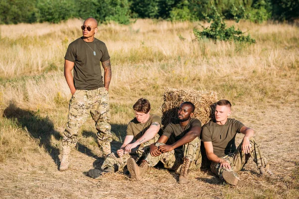 Multirazziale giovani soldati in uniforme militare a riposo sul campo — Foto stock