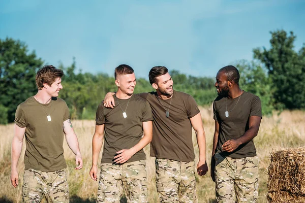 Portrait of multicultural smiling soldiers in military uniform on range on summer day — Stock Photo