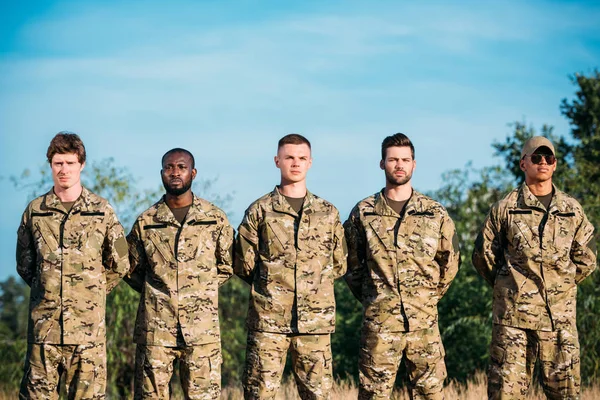 Портрет багаторасових впевнених солдатів у військовій формі, що стоять на дистанції — стокове фото