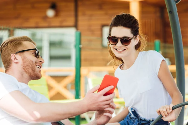 Joven guapo mostrando smartphone a novia - foto de stock