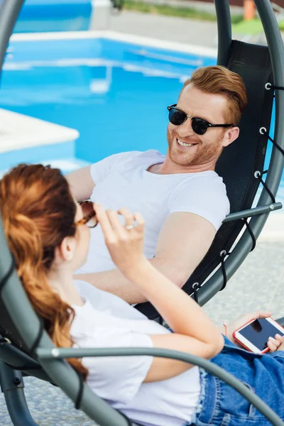 Jeune couple en t-shirts blancs flirtant devant la piscine — Photo de stock