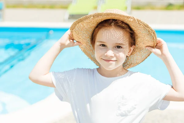 Adorable little child in straw hat in front of swimming pool — Stock Photo