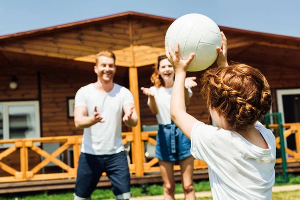 Маленькая девочка играет в волейбол с родителями в саду — стоковое фото