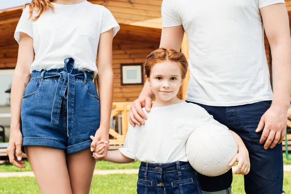 Adorable petite fille avec ses parents tenant ballon de volley-ball et regardant caméra — Photo de stock