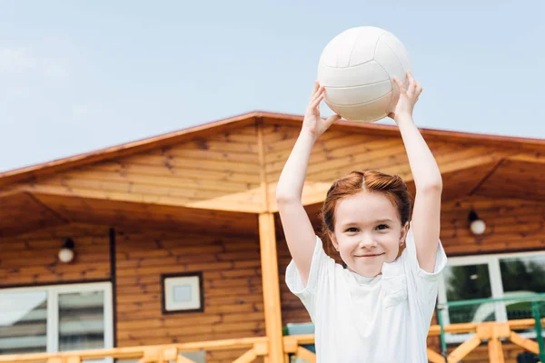 Очаровательный маленький ребенок с волейбольным мячом смотрит в камеру — стоковое фото