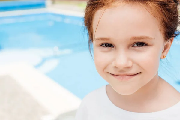 Close-up portrait of happy little child in front of swimming pool — Stock Photo