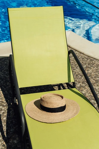 Sombrero de paja tumbado en la tumbona junto a la piscina - foto de stock