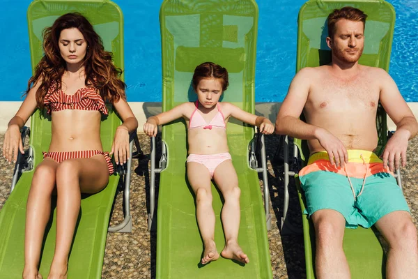 Relaxed young family tanning on sun loungers together — Stock Photo