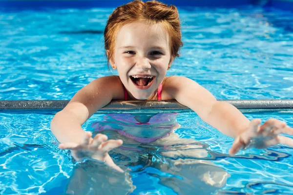 Retrato de cerca de un niño adorable en bikini en la piscina mirando a la cámara - foto de stock