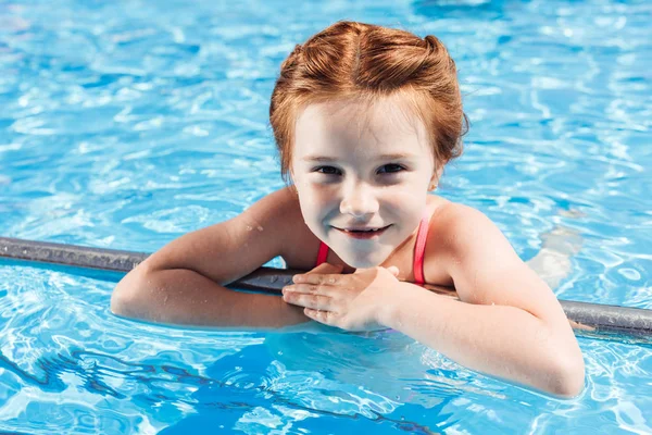 Retrato de primer plano de niño feliz en bikini en la piscina mirando a la cámara - foto de stock