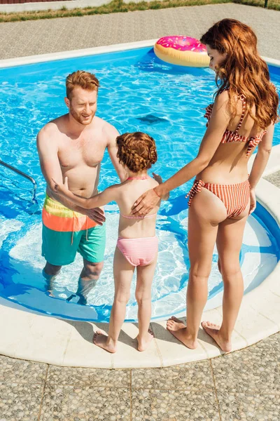 Красивая молодая семья, проводящая время вместе у бассейна — стоковое фото