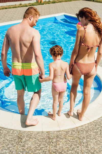 Visão traseira da jovem família que vai para a piscina — Fotografia de Stock