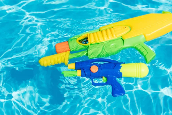 Pistolas de água coloridas de plástico flutuando na piscina — Fotografia de Stock