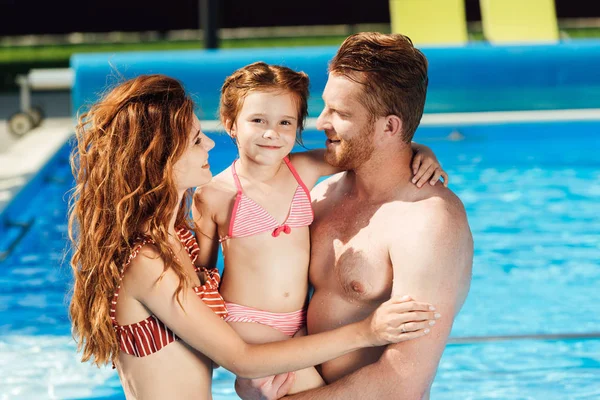 Hermosa familia joven abrazándose en la piscina - foto de stock