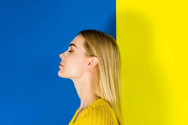 Portrait de fille blonde avec les yeux fermés sur fond bleu et jaune — Stock Photo