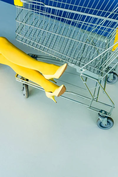 Cropped view of female legs in pantyhose by shopping cart — Stock Photo