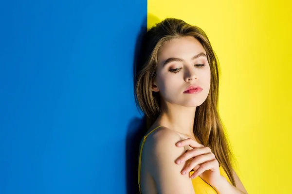 Menina morena bonita posando no fundo azul e amarelo — Fotografia de Stock