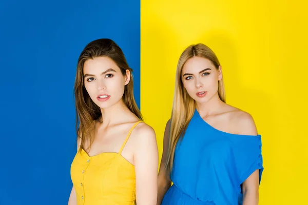 Girls in blue and yellow summer clothes isolated on blue and yellow background — Stock Photo