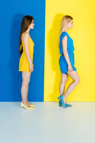 Female fashion models in contrasting clothes on blue and yellow background — Stock Photo