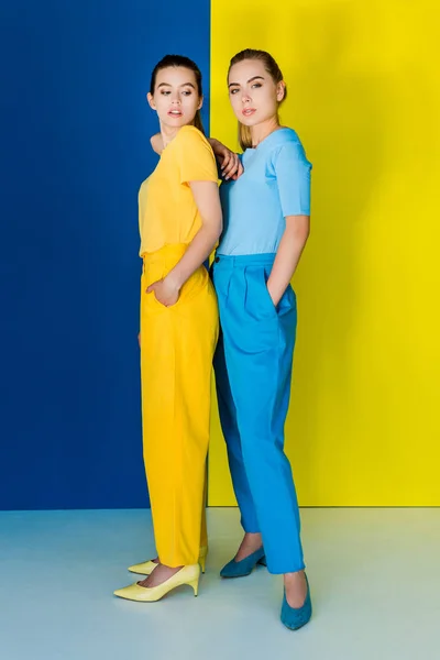 Eleganti donne alla moda in abiti a contrasto in posa su sfondo blu e giallo — Foto stock