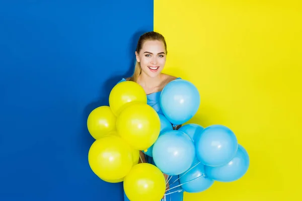 Modelo de moda feminina segurando balões de festa em fundo azul e amarelo — Fotografia de Stock