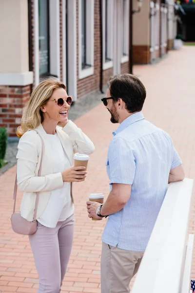 Coppia sorridente in piedi con tazze di caffè usa e getta sulla strada — Foto stock