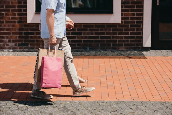 Обрезанное изображение пары, идущей с сумками на улице — стоковое фото