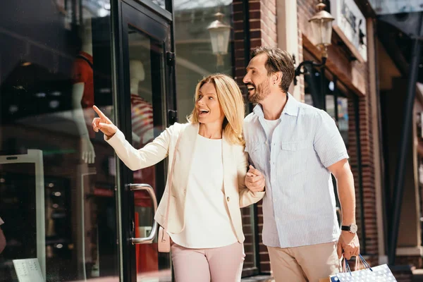 Frau zeigt von Straße auf Schaufenster eines Geschäfts — Stockfoto