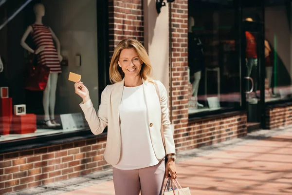 Attraktive Frau mit Kreditkarte und Einkaufstaschen auf der Straße — Stockfoto