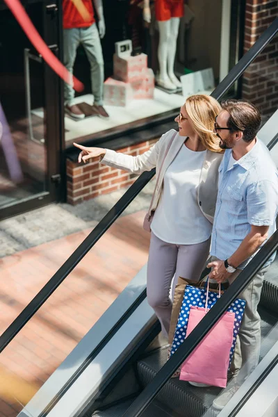 Vue grand angle de femme pointant sur quelque chose au mari dans le centre commercial — Photo de stock