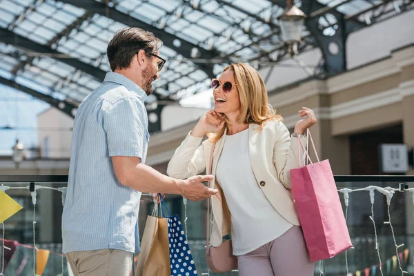 Happy couple in sunglasses talking in shopping mall — Stock Photo