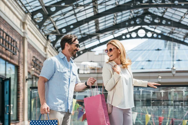 Happy couple in sunglasses looking at each other in shopping mall — Stock Photo