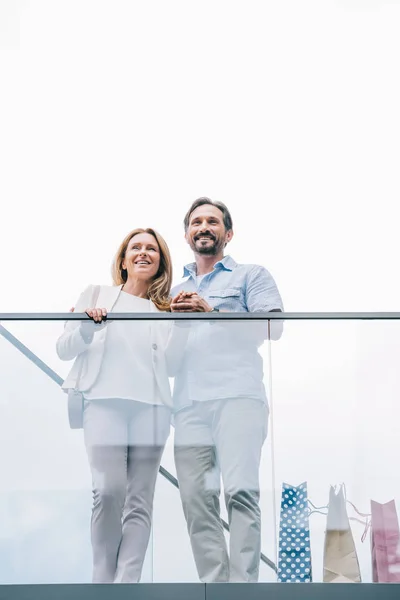 Baixo ângulo vista de casal em pé na varanda do shopping — Fotografia de Stock