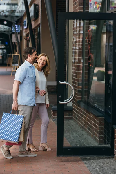 Vista lateral do casal que entra no shopping — Fotografia de Stock