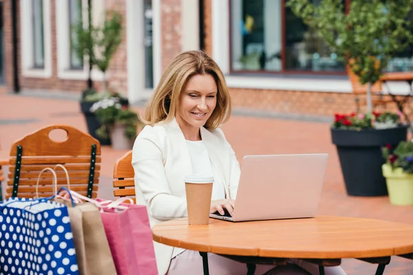 Atractiva mujer que trabaja con el ordenador portátil en la mesa en la cafetería - foto de stock