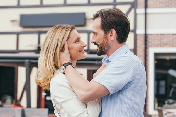 Side view of affectionate adult couple going to kiss in city — Stock Photo