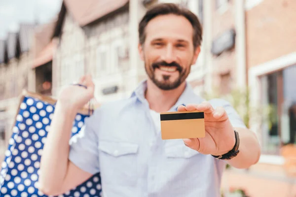 Sorrindo bonito homem mostrando cartão de crédito — Fotografia de Stock