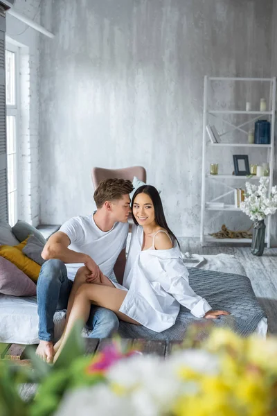 Junges multikulturelles Paar sitzt morgens im Schlafzimmer auf dem Bett — Stockfoto