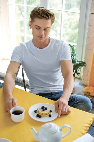 Retrato de homem pensativo sentado à mesa com café da manhã em casa — Fotografia de Stock