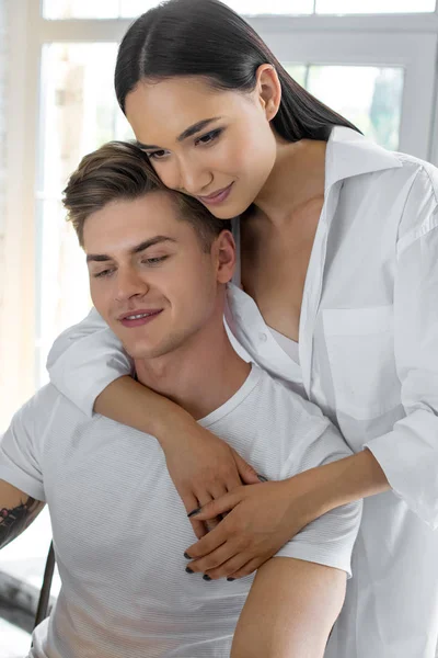 Retrato de mujer asiática abrazando caucásico novio en casa - foto de stock