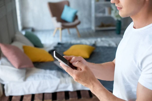 Side view of young man using smartphone at home — Stock Photo