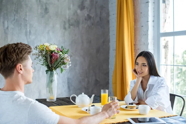 Vista lateral de la joven pareja multirracial desayunando juntos en casa - foto de stock