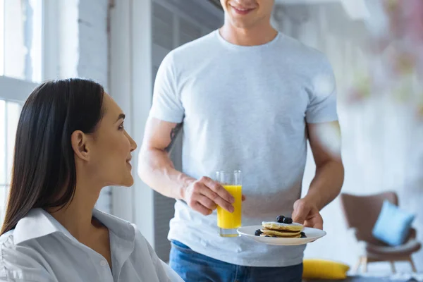 Cortado tiro de homem trouxe café da manhã para asiático namorada no branco camisa no mesa em casa — Fotografia de Stock