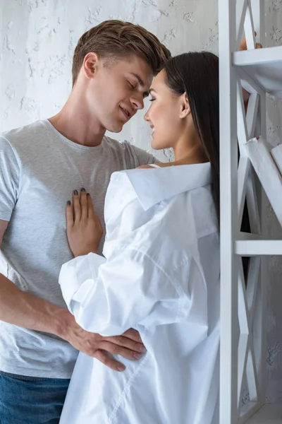 Vista lateral de la joven pareja multirracial abrazándose en casa - foto de stock