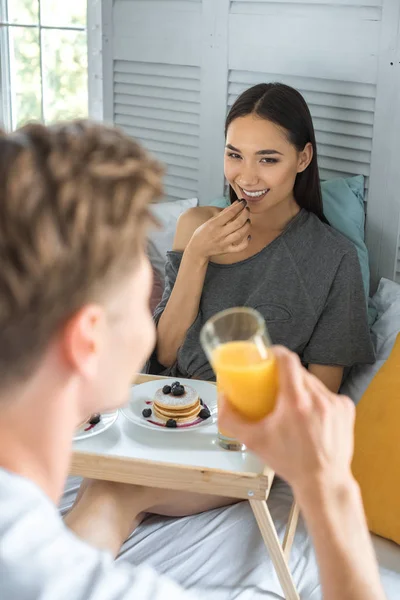 Vista parcial de pareja desayunando en la cama juntos en casa - foto de stock