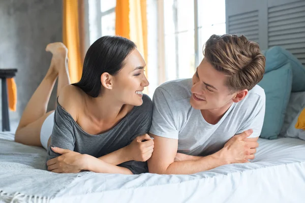 Portrait of multiracial couple lying on bed together in bedroom — Stock Photo