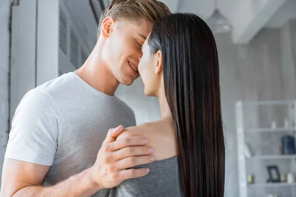 Vue latérale du couple multiculturel embrasser à la maison — Photo de stock